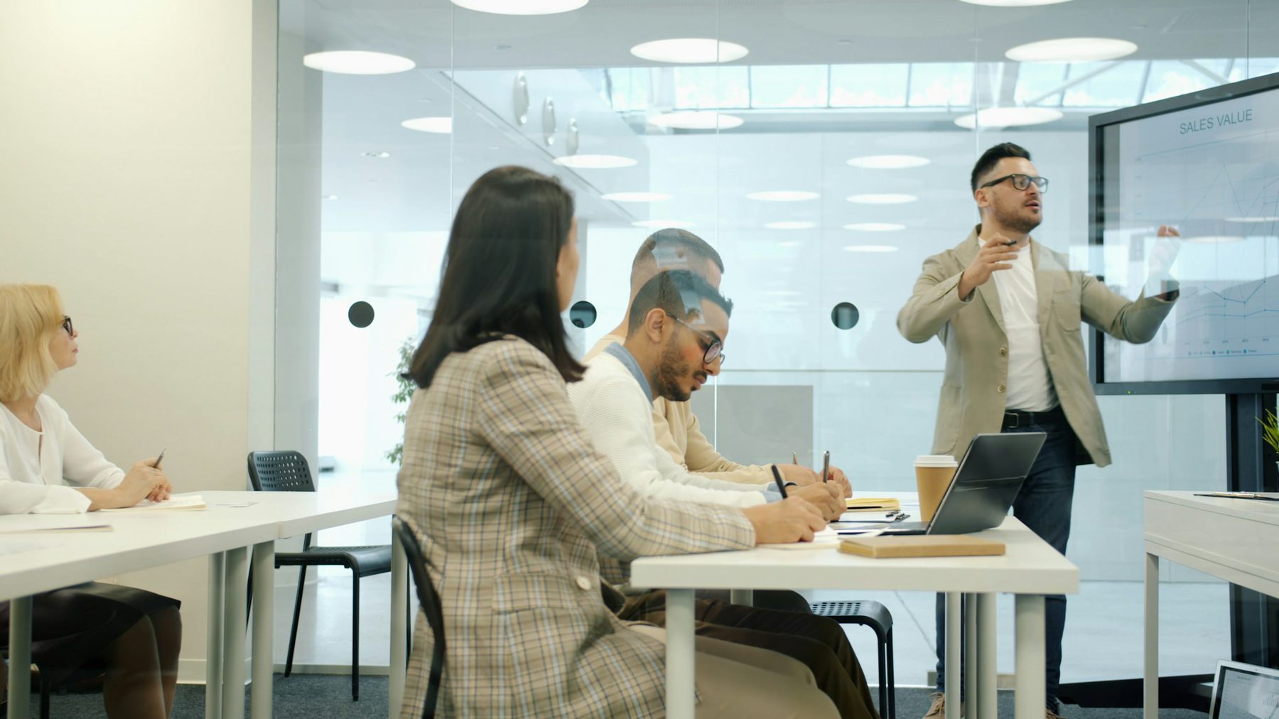 A trainer presenting to colleagues in a modern office meeting room