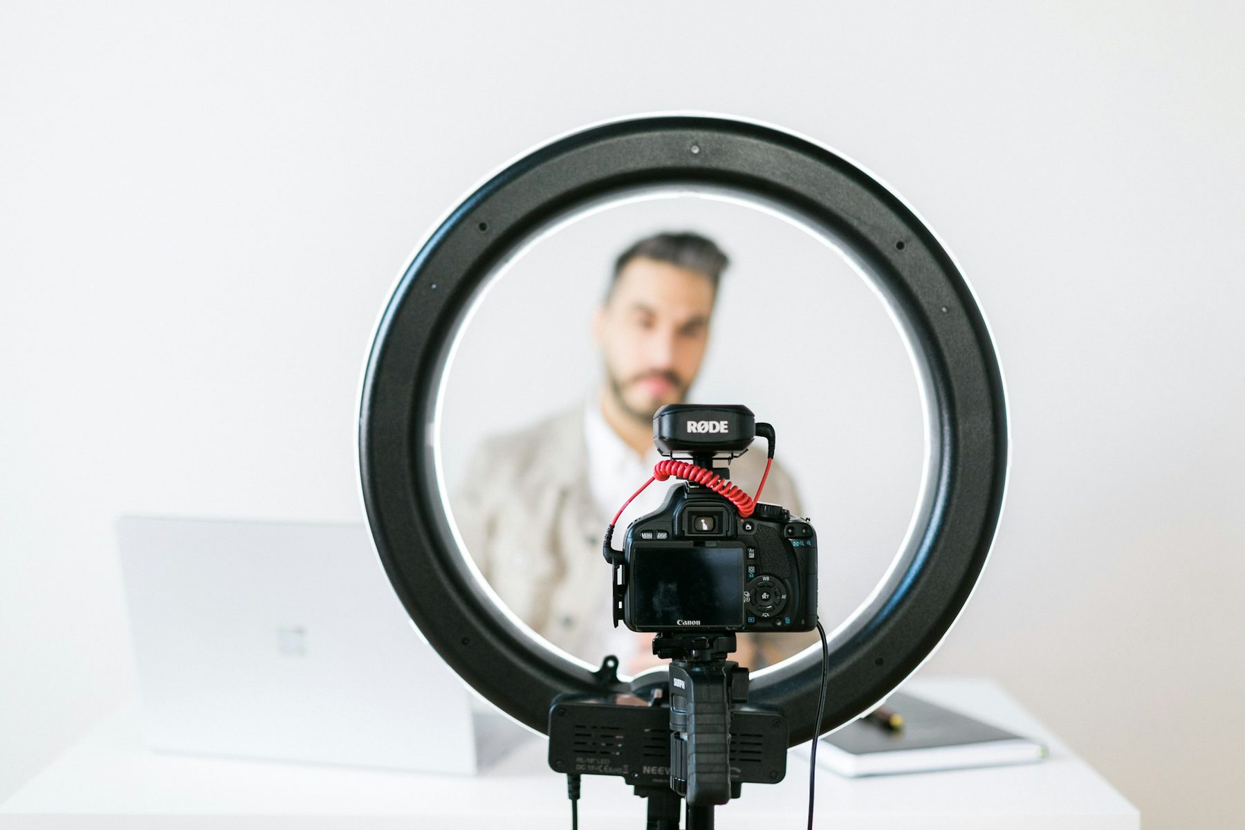 A ring light and camera set up to record a presenter at a desk