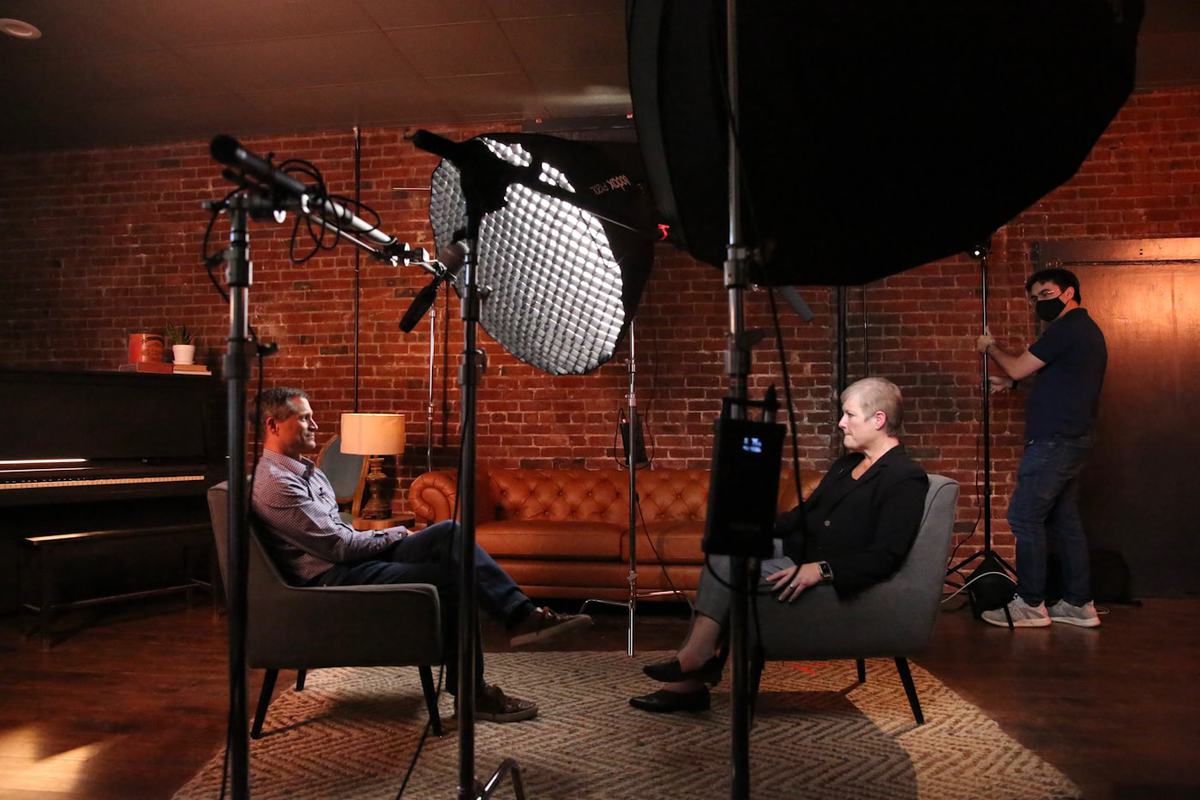 Two people recording a seated interview under studio softboxes